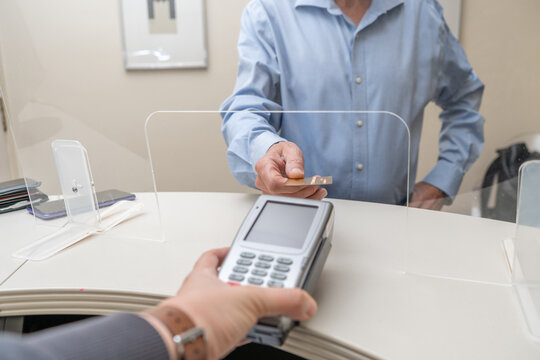 adult man paying for visit in dentist office in the medical clinic with card