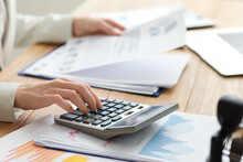 Female Accountant Working With Calculator And Documents At Table In Office, Closeup