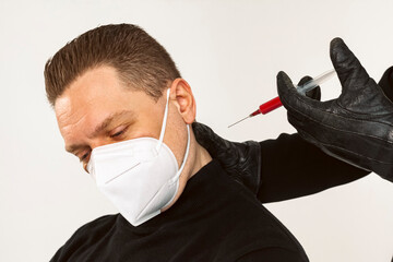 Wall Mural - Plague doctor giving an injection to a man in a Medical mask or respirator.a syringe and needle with Medicine or serum,antidote. Isolated on a white background.COVID-19, epidemic and pandemic concept.