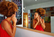 beautiful young black brazilian afro hairstyle woman putting on earrings in front of the mirror before going out	