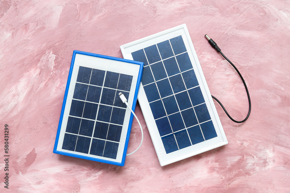 Portable solar panels with cables on pink grunge background