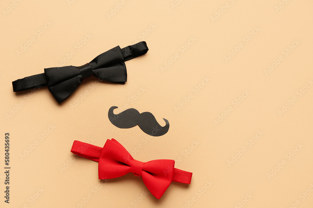 Stylish bow ties and paper mustache on color background