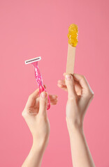 hands holding spatula with sugaring paste and razor on pink background. hair removal concept