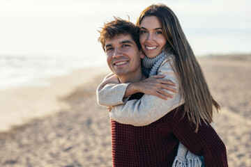 Beautiful young couple in love enjoying the day in a cold winter on the beach.