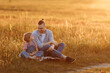 © Kaplitskaya Love - A touching moment, captured in time, when a little girl in denim overalls sits with her father in the field, they enjoy a walk in the field on a summer evening.