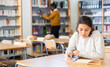 © JackF - Portrait of young adult woman studying in at public library