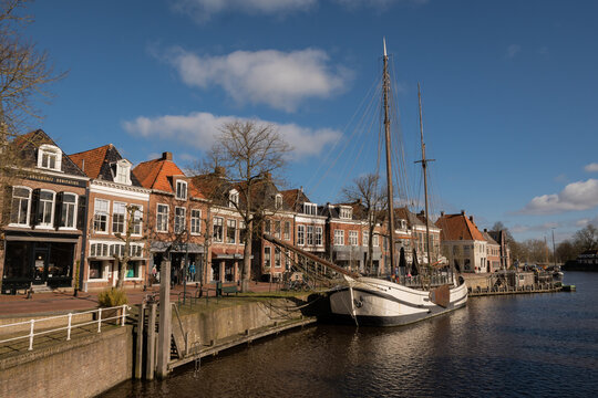 waterside residential houses and shops on the edge of the river grootdiep with ship Stichting Tromp waterway in Dokkum, Friesland, Netherlands Holland. town centre with bridge on pleasant sunny day