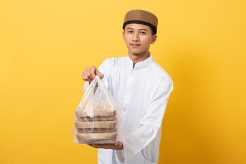 Wall Mural - Young handsome asian muslim man giving alms or charity standing over orange background. happy ramadan and eid al-fitr.