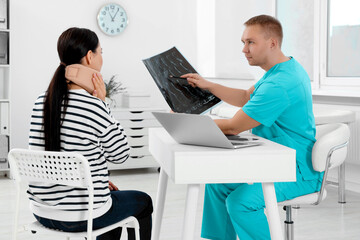 Doctor with neck MRI image consulting patient in clinic