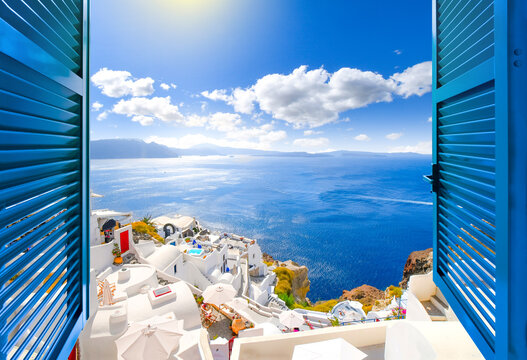 hillside view through an open window with blue shutters of the caldera, sea and white village of oia