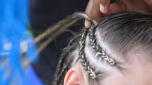 Close-up Of The Hands Of An Experienced Black Master Tightly Braiding A Thin Braid To A Woman Using Artificial Materials. African Hairdresser Weaves Popular Afro-braids To A Woman