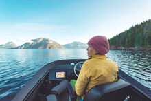 Woman Driving Motor Boat At Sunset In Coastal British Columbia In Nature Landscape Near Bute, Toba Inlet And Campbell River. Whale Watching Tourist Travel Destination, Canada