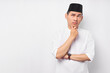 © Bangun Stock Photo - Portrait of pensive young Asian Muslim man looking at empty space, touching his chin, thinking about offer isolated on white background. People religious Islamic lifestyle concept
