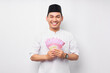 © Bangun Stock Photo - Portrait of smiling handsome young Asian Muslim man holding cash money rupiah banknotes isolated on white background. People religious Islamic lifestyle concept