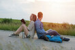 © Cavan Images - Full length side view of hiking couple sitting back to back on country road by field