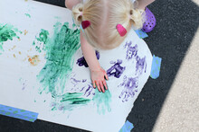 High Angle View Of Playful Girl Finger Painting On Paper At Street