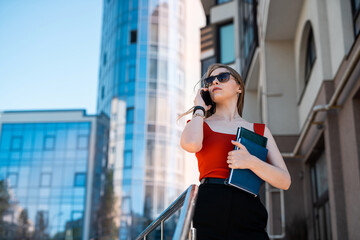 A beautiful business woman with a mobile phone is walking in the buildings in the city center