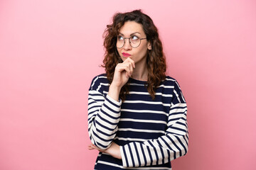 Wall Mural - Young caucasian woman isolated on pink background having doubts and with confuse face expression