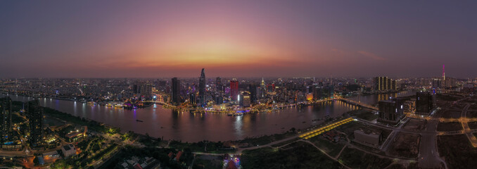 Ho Chi Minh City, Vietnam iconic Skyline and Saigon river waterfront aerial panorama on a busy evening featuring all key buildings illuminated against beautiful colored sky and reflected in the river