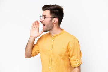 Wall Mural - Young caucasian man isolated on white background shouting with mouth wide open to the side