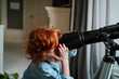 © Westend61 - Redhead boy looking through telescope at home