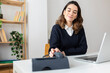 © Westend61 - Smiling businesswoman holding telephone receiver at desk