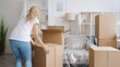 © golubovy - Home relocation. Moving day. Removal service. Unrecognizable woman carrying carton boxes in light modern apartment with covered furniture.