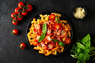 Wall Mural - Fusilli pasta with tomatoes, basil, parmesan, and sauce on back background