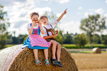 Two kids, boy and girl in traditional Bavarian costumes in wheat field