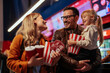 © bernardbodo - Joyful family purchasing popcorn and beverage in cinema.
