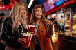 © bernardbodo - Female friends paying with mobile phone in cinema.