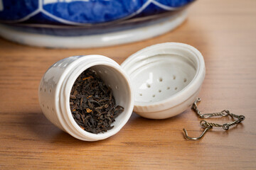 Canvas Print - White ceramic open tea strainer with dried Chinese Kee Mun tea leaves close up