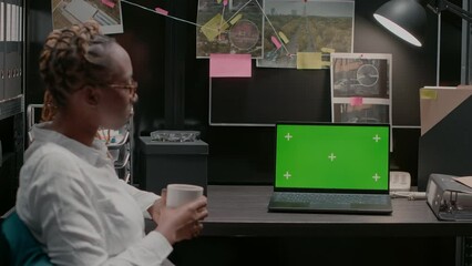 African american agent using greenscreen on laptop, analyzing isolated display and conducting criminal investigation. Female detective working with blank chroma key mockup screen.