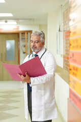 Wall Mural - Indian senior doctor watching medical report at hospital.