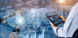 © panuwat - Smart industry control concept.Manager Engineer Hands holding tablet on blurred automation machine as background