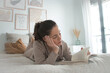 © Anna - Woman relaxing on a bed reading a book