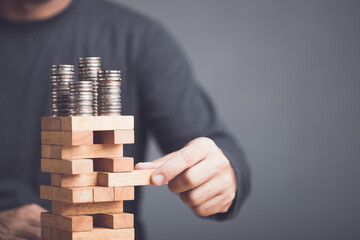 Risks in business or financial concept. Idea to prevent risk in business. Business man playing and selective right or risky piece of tower wooden block game and prevent falling down.