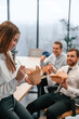 © standret - Woman is leaning on the table. Group of coworkers are eating food from eco boxes in the office together