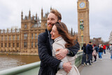 Fototapeta Londyn - Happy couple of young travelers embrace against the background of London's Big Ben
