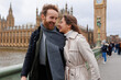 Happy young couple walks holding hands against the background of London's Big Ben