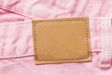 Wall Mural - Pink jeans denim texture with thread sew lines. Fashion background with empty copy space for graphic design. Blank leather label tag. Brown clothing tag.