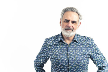 Studio shot of an older bearded grey-haired man in a blue patterned button-up shirt with hands on his waist. Smiling. Isolated on a white background. High-quality photo.