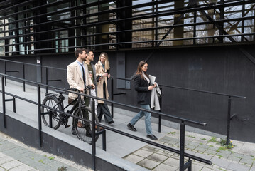 Wall Mural - Group of business people walking outside in front of office buildings. Successful colleagues talking about new project promotion of their work and business ideas and solutions