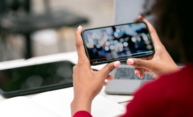 Wall Mural - cropped shot of young woman watching video on her smartphone in horizontal view.