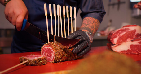 Wall Mural - Skewered beef roulade scliced and prepared for barbeque. Male cutting rolled beef spiced with mixed peppers.