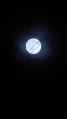 Wall Mural - Airplane crossing the moon at night with trail. Telephoto view of a passenger jet flying against the bright full moon on the mysterious cloudy sky. Plane silhouette, black background and copy space.