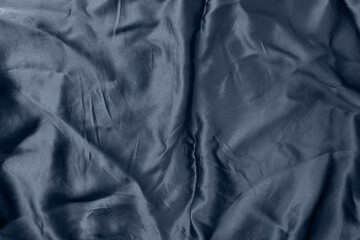 Crumpled dark blue silk satin fabric texture. Navy blue abstract textile background, top view