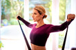 © gzorgz - Mid aged woman exercising with a power band at home