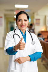 Wall Mural - Indian female doctor showing thumps up at hospital.