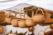 Group Of Hanging Empty Wicker Baskets In A Tent Or Stall For Sale In A Street Market Or Traditional Fair In Winter Or Spring Under The Snow